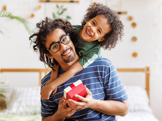 Cheerful ethnic  father and son celebrating Fathers Day together at home