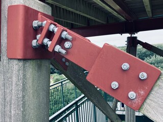 a steel joint fixes two wooden beams with several bolts and nuts 