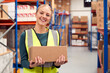 © Monkey Business - Portrait Of Female Worker Holding Box Inside Warehouse