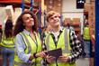 © Monkey Business - Male Intern With Team Leader Looking At Digital Tablet Inside Busy Warehouse Facility