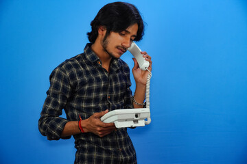 handsome young man talking by telephone on blue background