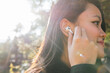 © ADDICTIVE STOCK - Ethnic woman putting wireless earbuds in ear