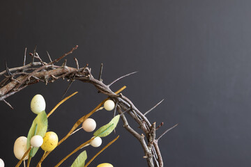 Wall Mural - Partial crown of thorns and decorative branch with easter eggs on a black background with copy space