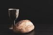 Loaf of bread and clay chalice on a black background with copy space