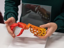 A Woman Demonstrates A Plastic Children's Prosthetic Hand Printed On A 3D Printer. 