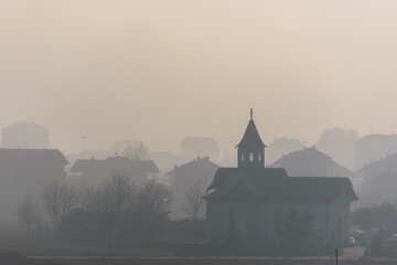 View of the small church in the city on a foggy day in Chivasso, Italy