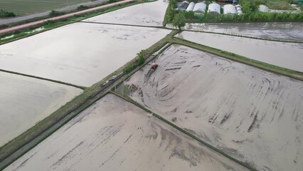 Wall Mural - Farmer tractor plowing soil to prepare the field for cultivate rice in plantation at countryside