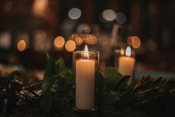 Close-up shot of a decorative candles among fake plants on a blurred background