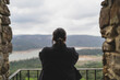 Chica joven guapa en balcón de piedra mirando zona montañosa en pueblo blanco andaluz