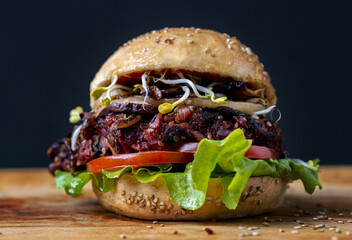 Canvas Print - Closeup shot of the delicious vegan burger with lettuce, tomato, and onions on the wooden surface