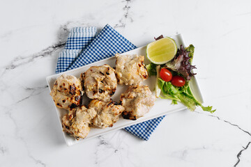 Wall Mural - Malai Chicken Kebab bbq with lime in a dish isolated on napkin side view on grey background