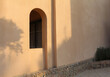 An arch window in the wall of the arabic building. Summer floral shadows on the wall.