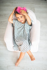 cute little girl sitting on small armchair and smiling at camera.