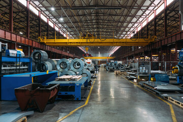 Metalworking factory production line. Rolls of steel and metal profiled parts in workshop