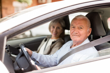 Caucasian senior couple sitting in car. Old man sitting on driver's seat.