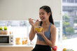 © chokniti - young Asian woman cooking vegetable healthy food and eating or drinking in home kitchen