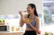 © chokniti - young Asian woman cooking vegetable healthy food and eating or drinking in home kitchen
