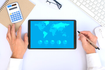 Poster - Man looks at infographics on a tablet computer that show various business statistics with world map