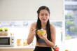 © chokniti - young Asian woman cooking vegetable healthy food and eating or drinking in home kitchen
