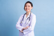 © Timeimage - Young Asian female doctor standing on blue background
