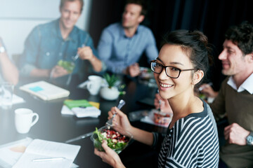 Poster - enjoying a team lunch. portrait of a young office worker eating lunch with coworkers at a boardroom 