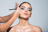 Sexy makeup for party. Makeup artist applies eye shadow. Hand of visagiste, painting cosmetics of young beauty model girl. Beautiful sensual young woman with sexy make up, close-up portrait.