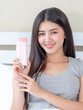 © suphaporn - Young beautiful woman holding and skin lotion in her hand and smiling with happiness, copy space