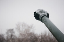 The Barrel Of An Artillery Gun During A Snowfall. The Contours Of Trees Are Blurred In The Background. Snowflakes Are Falling.