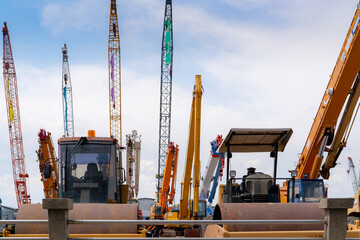 Road roller, mobile crane, and backhoe with long boom. Heavy machinery parked at second-hand machinery auction yard. Road roller, mobile crane, and digger for rent and sale. Construction industry.