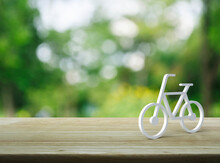 Bicycle 3d Icon On Wooden Table Over Blur Green Tree In Park, Business Bicycle Service Concept