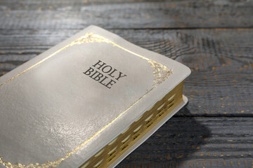 Old hardcover Bible on grey wooden table, closeup. Religious book