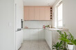 Kuchnia w minimalistycznym nowoczesnym stylu. Białe i różowe fronty mebli oraz sprzęt. Biała lodówka
