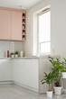 Detal na kuchnię w minimalistycznym nowoczesnym stylu. Białe i różowe fronty mebli oraz sprzęt. Donice z kwiatkami