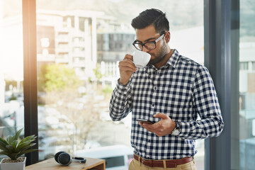 Aufkleber - Staying connected during his break. Shot of a young businessman using his cellphone while having coffee.