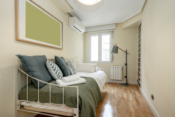 Wall Mural - Youthful metal bed with lots of cushions in a bedroom with parquet flooring and an air conditioner