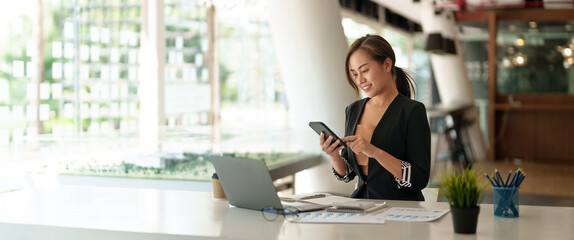 Business asian woman using mobile phone during checking an email or social media on internet. accounting financial concept.