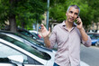 © JackF - Adult man is talking by phone and standing near his modern car outdoor.