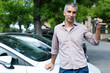 © JackF - Portrait of male who is standing satisfied with key near his car outdoor.