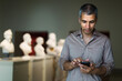 © JackF - Adult man is visiting museum and looking at the exposition with information on phone indoor.