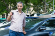 © JackF - Portrait of male who is standing satisfied with key near his car outdoor.