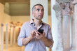 © JackF - Adult man is visiting museum and looking at the exposition with information on phone indoor.