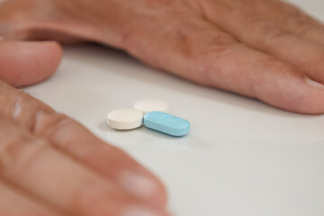 Wall Mural - Colored pills forming small male genitalia in the hands of a man on a neutral background. Male impotence treatment concept.