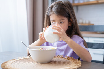 Wall Mural - Happy arab child girl having breakfast colorful cereal with milk at home on the morning