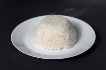 rice on white plate over black background studio