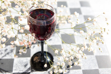 A glass of wine on a chessboard. Spring mood White Gypsophila on a black background