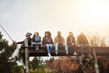 Wall Mural - Collect moments, not things. Shot of a group of friends sitting on a pier together on a weekend breakaway.