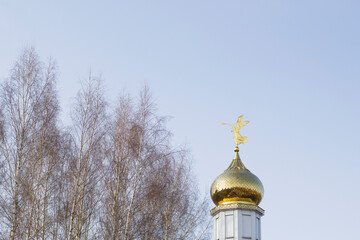 golden domes of orthodox church with blue sky and trees in early spring