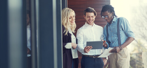Poster - Doing business on the balcony. Cropped shot of three young businesspeople using a tablet while standing outside on the office balcony.