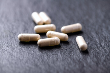 Wall Mural - Maca capsules. Concept for a healthy dietary supplementation. Dark stone background. Soft focus. Close up.