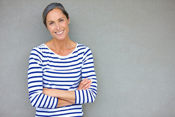 Confident beauty. Portrait of an attractive mature woman in casualwear standing against a gray wall.